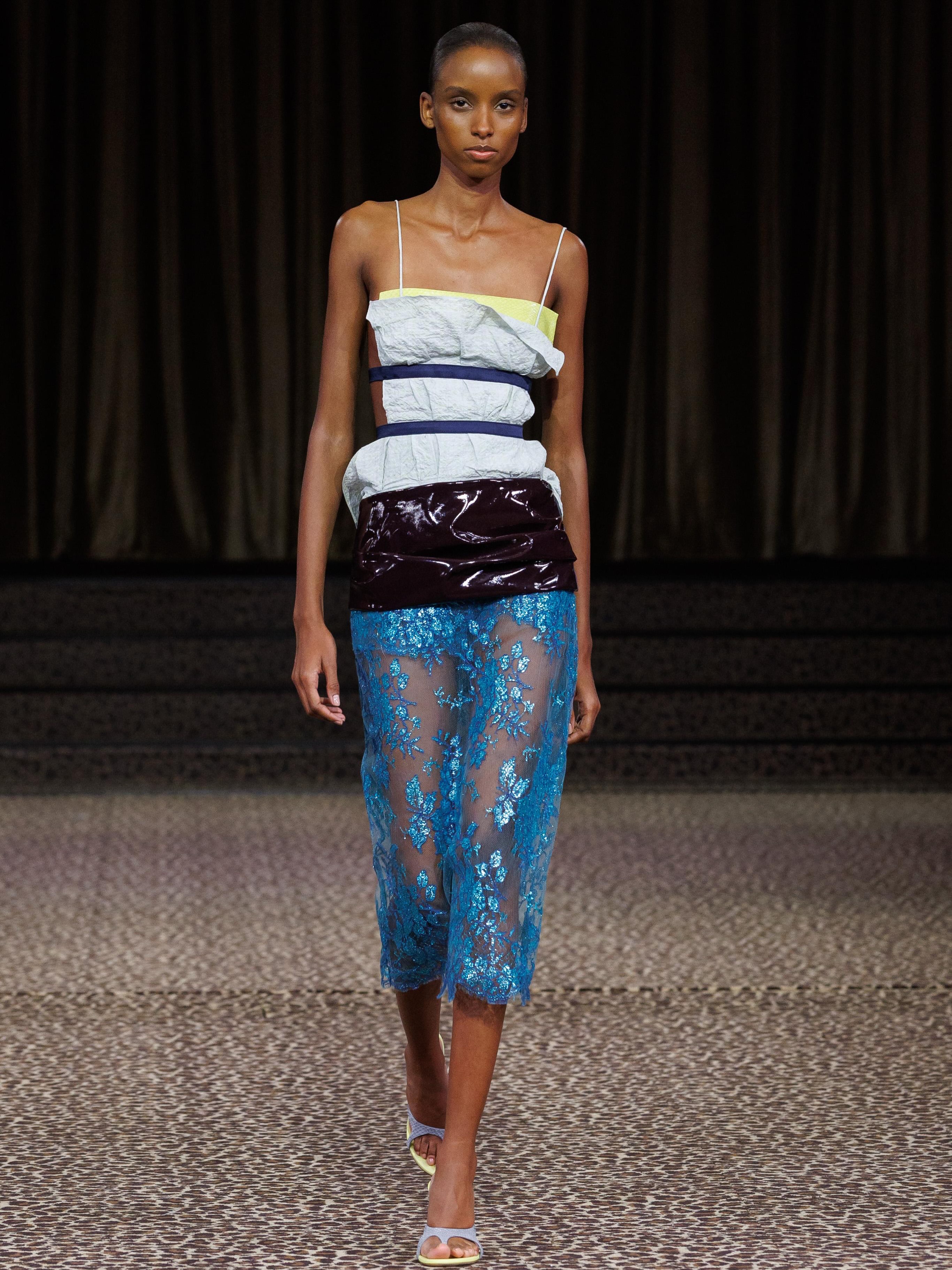 For spring summer 2027, Christopher Esber looks to the small language of dress, a pocket square, a cuff, a belt, a stud, and blows each detail out of proportion.

Familiar codes are enlarged, displaced and reconstructed, becoming the very architecture of the clothes. Elongated tailoring, exploding cuffs, high-split a-line skirts, sculptural belts and fluid lace blur the line between construction and disruption.

Menswear meets lingerie, structure meets transparency, with ceramic-coated lace, sheer georgette, shredded leather and archival 1950s studs bringing tension to the silhouette.

In collaboration with artist Anna Studeli, collage imagery is translated onto satin-backed PVC, adding another layer between the familiar and the abstract.

Presented beneath an oval skylight in an underground Paris theatre, across leopard carpet, Christopher Esber’s ss27 is a study in how one small detail can shift the entire shape of a garment.

Creative Direction @christopher_esber 
Styling @ilona_hamer 
Production @twotwenty_production